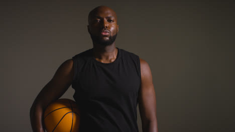Studioporträtaufnahme-Eines-Männlichen-Basketballspielers,-Der-Den-Ball-In-Richtung-Kamera-Hält-1